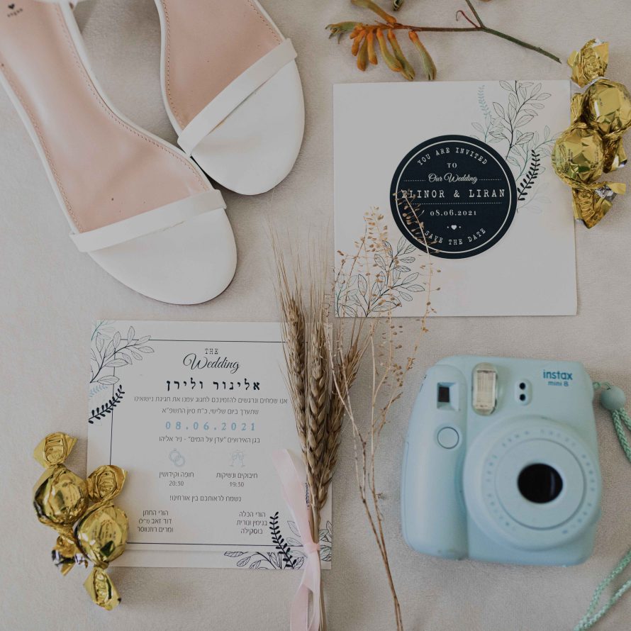 Bridal shoes, a wedding invitation, a bunch of oats, a Polaroid camera and chocolates in a golden wrapper
