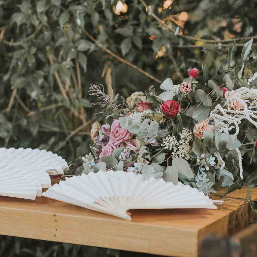 White fans and an flowers arrangement on a wooden table