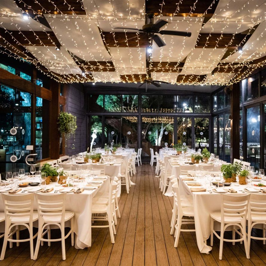 Styled tables in a transparent balcony with a ceiling illuminated by Christmas lights
