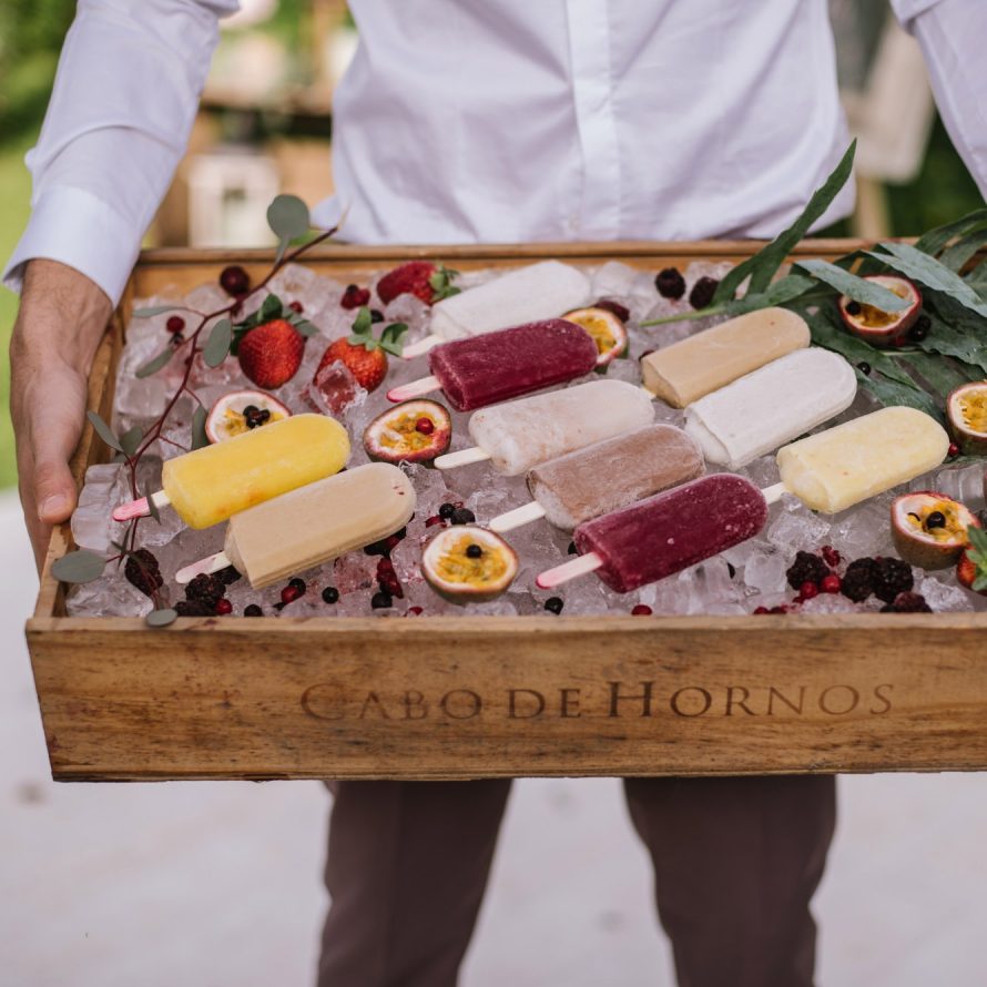 A man holds a wooden tray with natural popsicles on ice bed