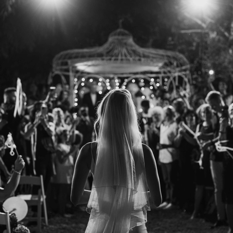 Back view of a bride in front of the canopy surrounded by guests