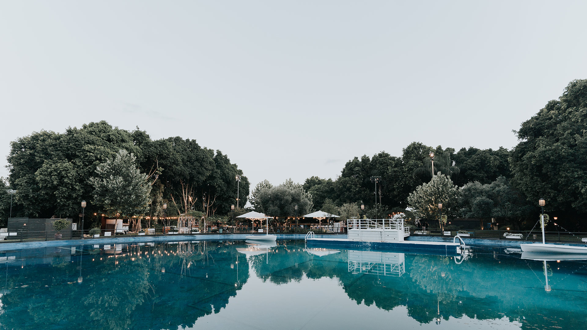 Reflection of trees and reception area on a blue water pool