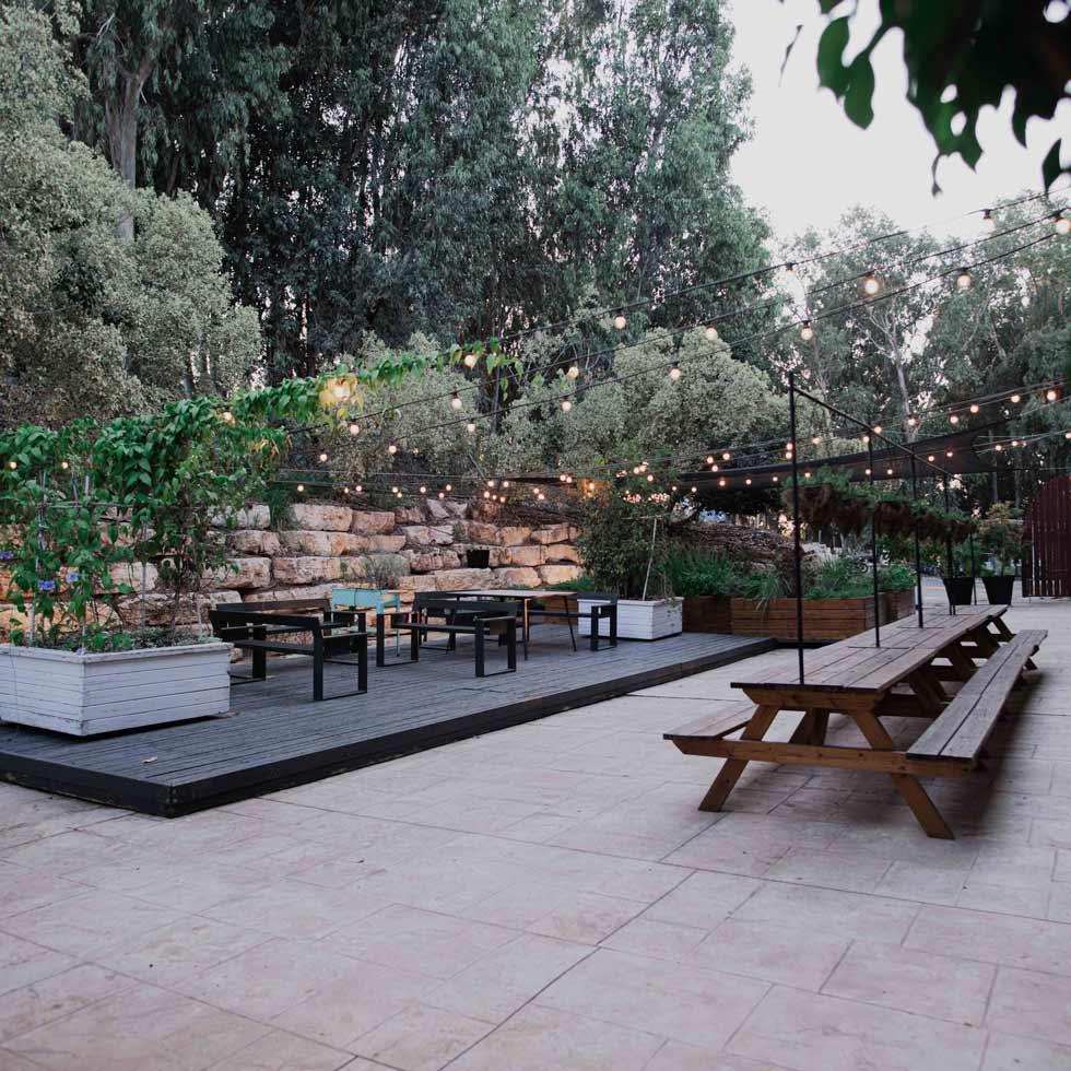 Picnic tables and a deck platform with seating areas next to a rockery surrounded by eucalyptus trees