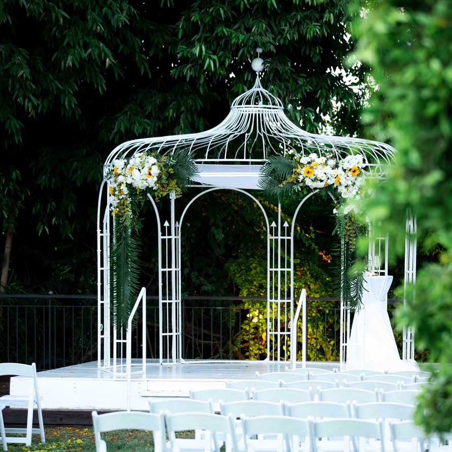 Hupa in a gazebo decorated with flowers, on a white platform and green vegetation in the background