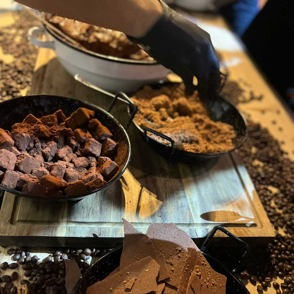 Dishes with chocolate twill, cubes of truffles, and cocoa streusel on a wooden board and coffee beans