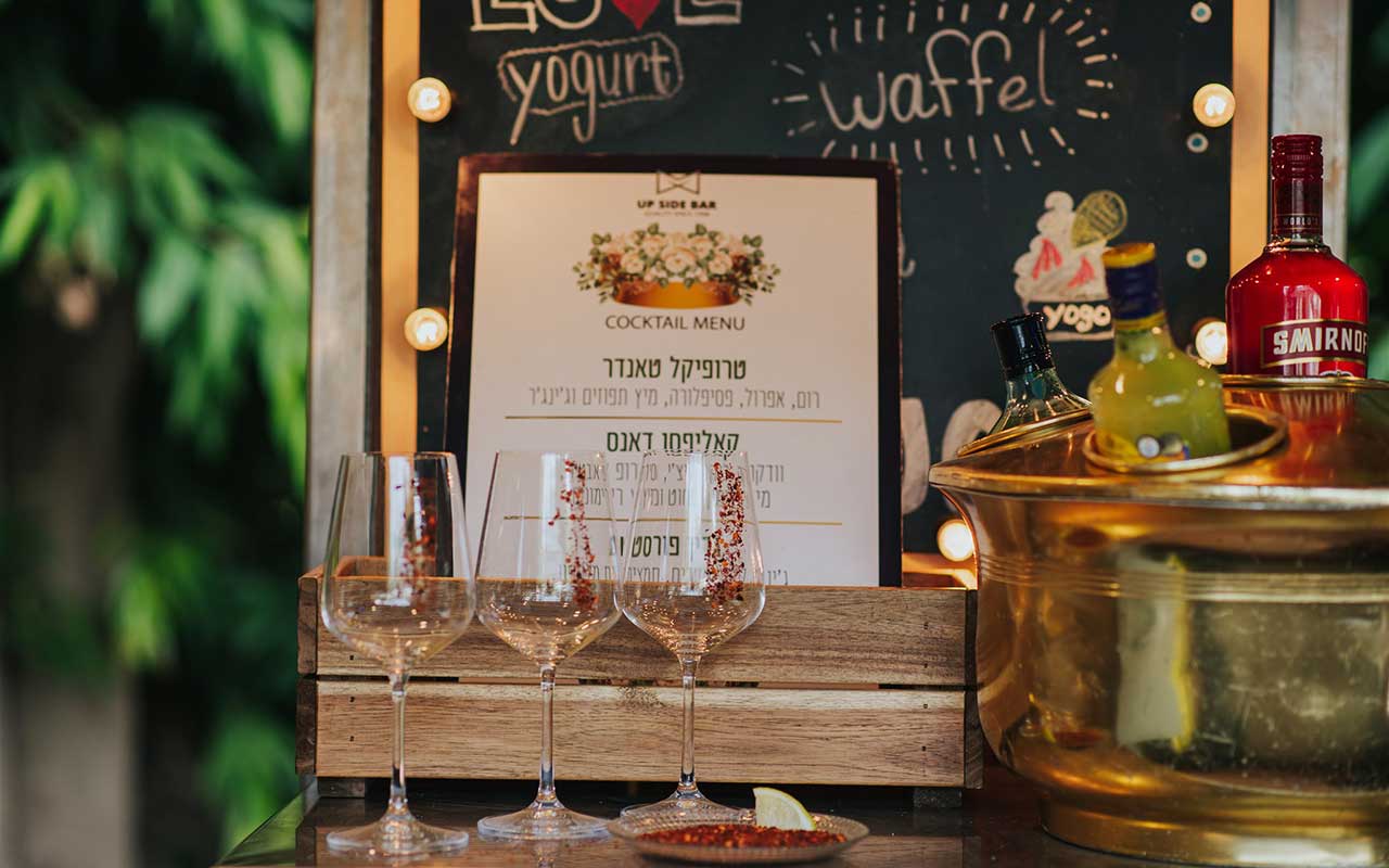 כוסות קוקטייל מקושטות בנצנצים על רקע תפריט קוקטיילים